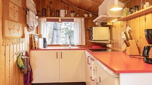 A kitchen with wooden cabinets, a red countertop, and a window with a view of trees.