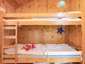 A bunk bed with a ladder, a star-shaped hanging decoration, and two plush toys on the lower bunk.