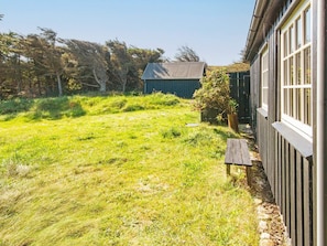 A grassy yard with a wooden bench and a small tree. - 4 Person Holiday Home in Ulfborg (Ulfborg)