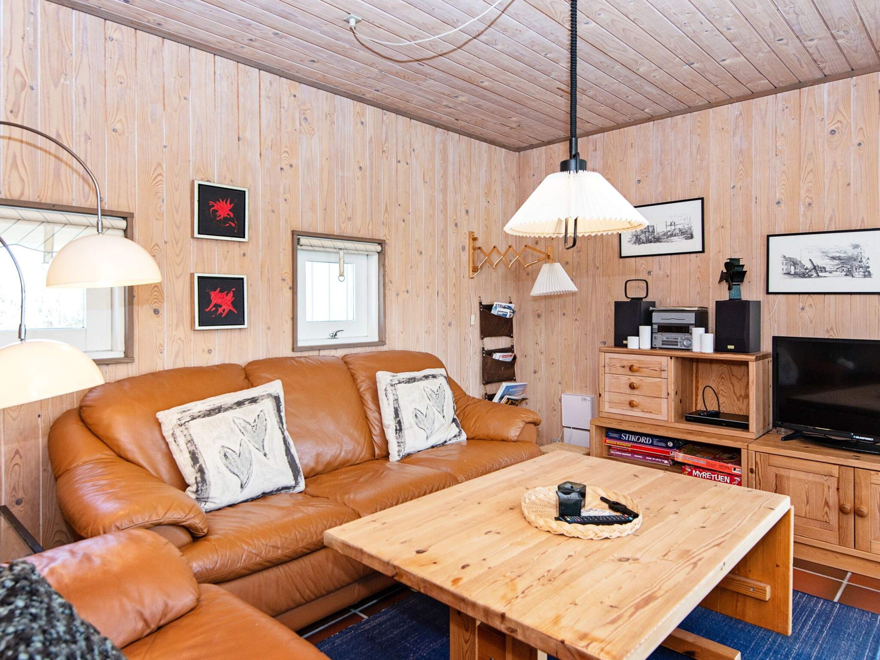 A cozy room with a brown leather sofa, a wooden coffee table, and a television.