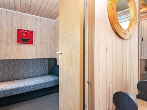 A wooden interior with a sofa, a mirror, and a red sign on the wall.