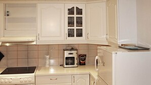 A kitchen with white cabinets, a stove, an oven, a coffee maker, and a refrigerator. - 5 Person Holiday Home in Selsoyvik (Rodoy)