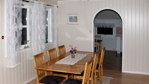 A dining area with a wooden table and chairs, a lace curtain, and a framed picture on the wall. - 5 Person Holiday Home in Selsoyvik (Rodoy)