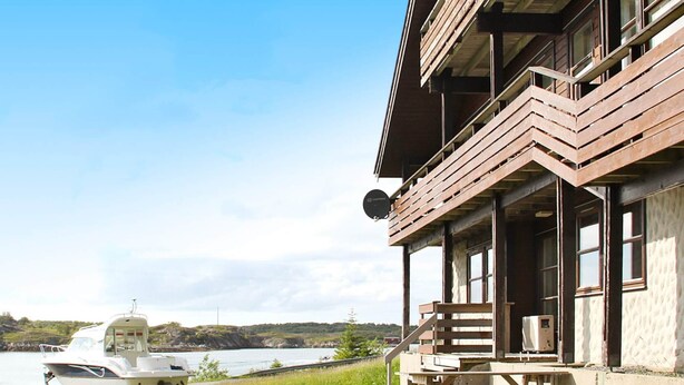 A building with a balcony, a boat, and a view of the water. - 5 Person Holiday Home in Selsoyvik (Rodoy)