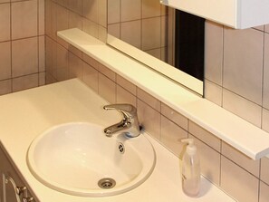 A bathroom with a white sink, chrome faucet, and a mirror above it.