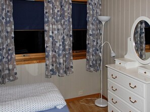 A bedroom with a bed, a dresser with drawers, a mirror, and curtains.