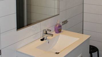 A bathroom with a white sink, a mirror, and a bottle of hand soap.
