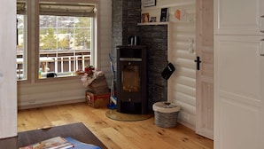 Ein gemütliches Zimmer mit Kamin, Holzboden, einem Fenster mit Ausblick und einer Tür.