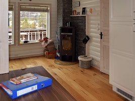 Una habitación acogedora con chimenea, piso de madera, una ventana con vistas y una puerta.