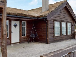 Una cabaña de madera con techo de paja, una puerta blanca y un pequeño balcón.