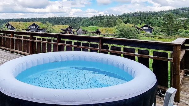 Ein aufblasbarer Pool auf einer Holzterrasse mit Blick auf Häuser und Grünflächen im Hintergrund.