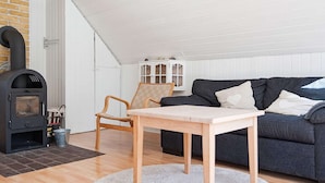 A cozy living room with a fireplace, a sofa, a table, and a chair. - 4 Person Holiday Home in Ebeltoft (Ebeltoft)