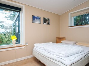A bedroom with a bed, a window, and two framed pictures on the wall.