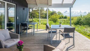 A covered outdoor patio with a table and chairs, a sofa, and a potted plant.