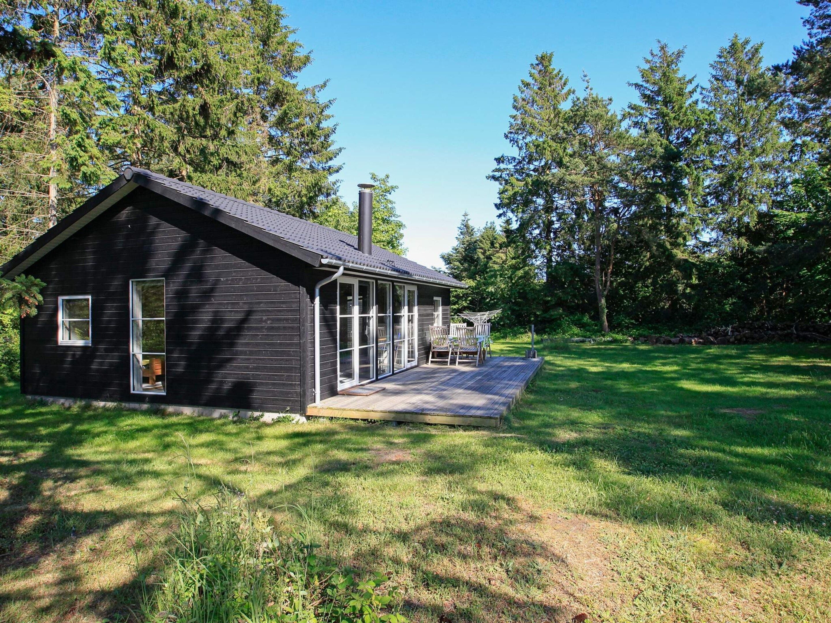 A small cabin with a porch, surrounded by trees.