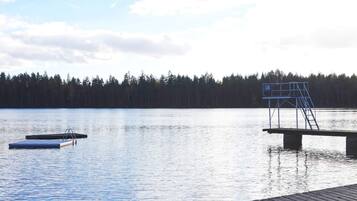 Un lago tranquilo con un muelle de madera y un puesto de salvavidas azul.