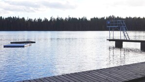 A calm lake with a wooden dock and a blue lifeguard stand. - 6 Person Holiday Home in Hallabro (Hallaröd)