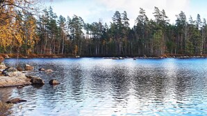 A calm lake surrounded by trees with a rocky shoreline. - 6 Person Holiday Home in Hallabro (Hallaröd)