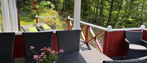 A covered outdoor deck with wicker furniture and a potted plant.