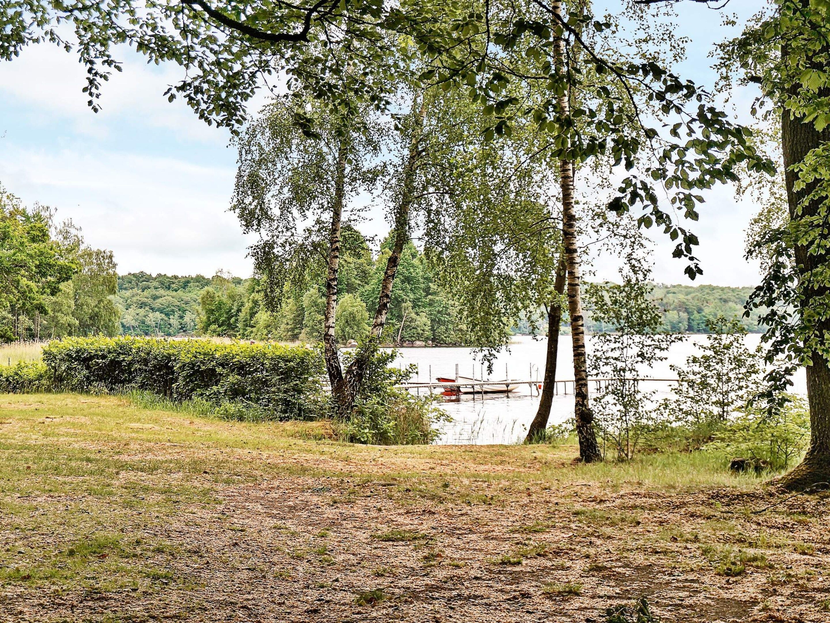 A natural landscape with a lake, trees, and a dock with boats.