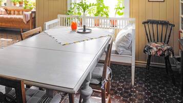 A dining area with a white table, wooden chairs, a bench, and a potted plant.