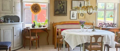 A dining area with a table set for four, a chandelier, and a view of the outdoors.