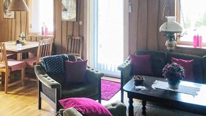 A cozy cabin interior with a dining area, a sofa set, and a table with a vase of flowers. - 6 Person Holiday Home in Savsjo (Savsjo)