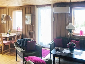 A cozy cabin interior with a dining area, a sofa set, and a table with a vase of flowers. - 6 Person Holiday Home in Savsjo (Savsjo)