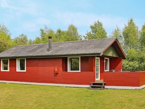 A red wooden cabin with a metal roof, a chimney, and a small porch. - 6 Person Holiday Home in Hadsund (Hadsund)