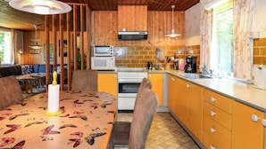 Una cocina con armarios de madera, microondas, estufa y una mesa de comedor con mantel de mariposas.