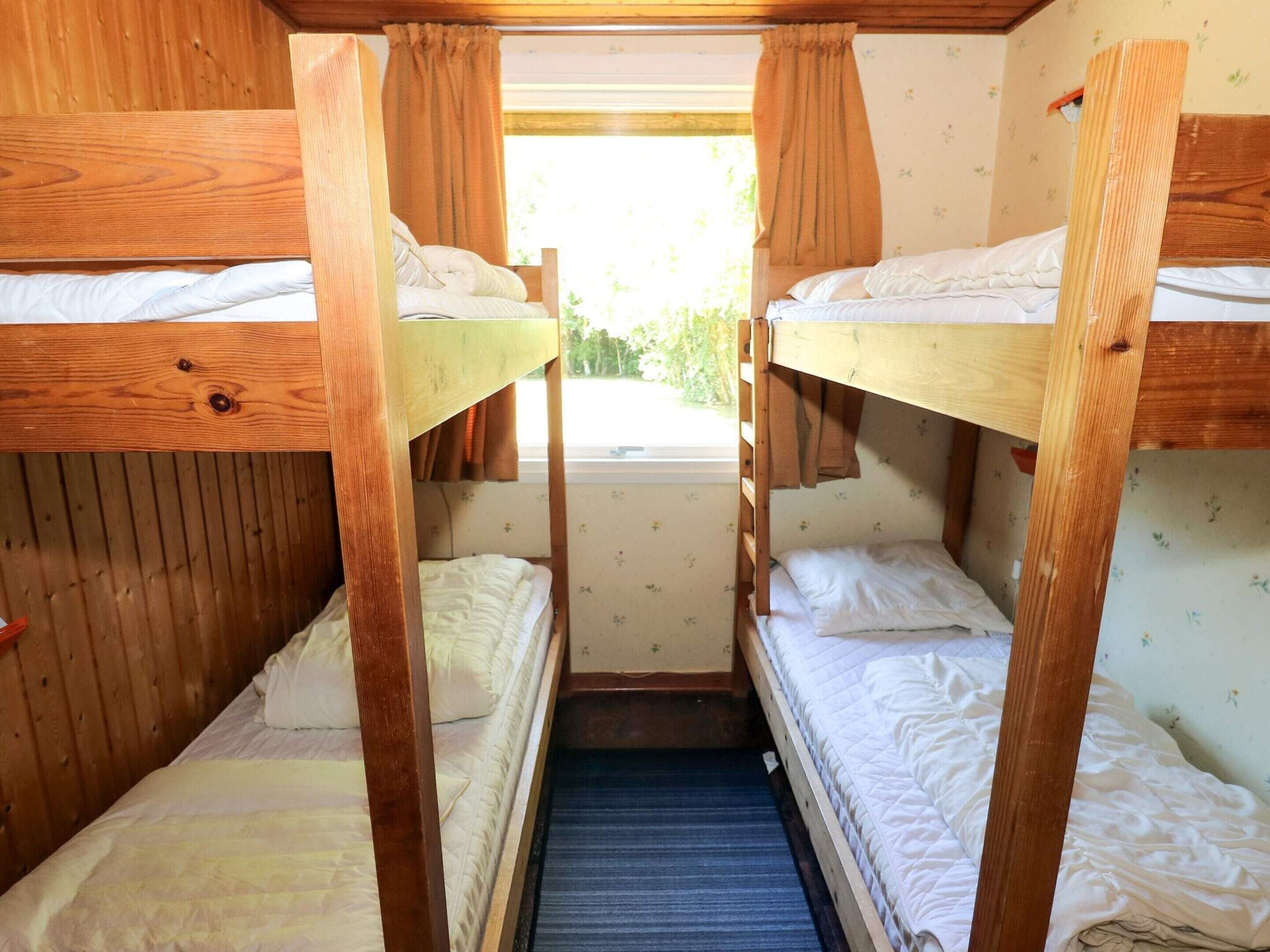 Dormitorio con literas de madera, una ventana y vista a zonas verdes.