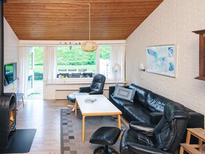 A modern living room with a fireplace, leather furniture, and large windows offering a view of the outdoors. - 6 Person Holiday Home in Aabenraa (Aabenraa)