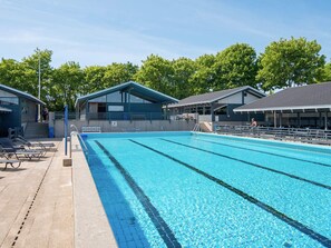A swimming pool with clear blue water, surrounded by lounge chairs and covered seating areas. - 6 Person Holiday Home in Aabenraa (Aabenraa)