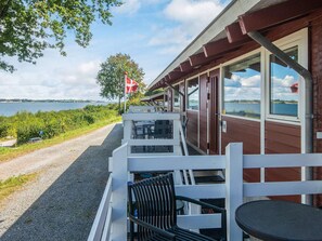 A seaside restaurant with outdoor seating, a flag, and a view of the water. - 6 Person Holiday Home in Aabenraa (Aabenraa)