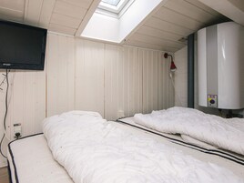 Una habitación con dos camas, un televisor montado en la pared y un calentador de agua.