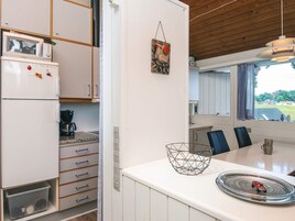 A compact kitchen with a microwave, coffee maker, and a dining area with a table and chairs.