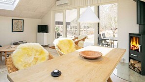 A modern living room with a fireplace, a dining table, and a television. - 4 Person Holiday Home in Laeso (Læsø)