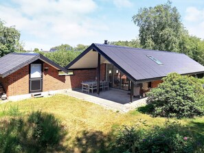 Ein zweistöckiges Haus mit Ziegelaußenwand, einer überdachten Terrasse und einem kleinen Garten.