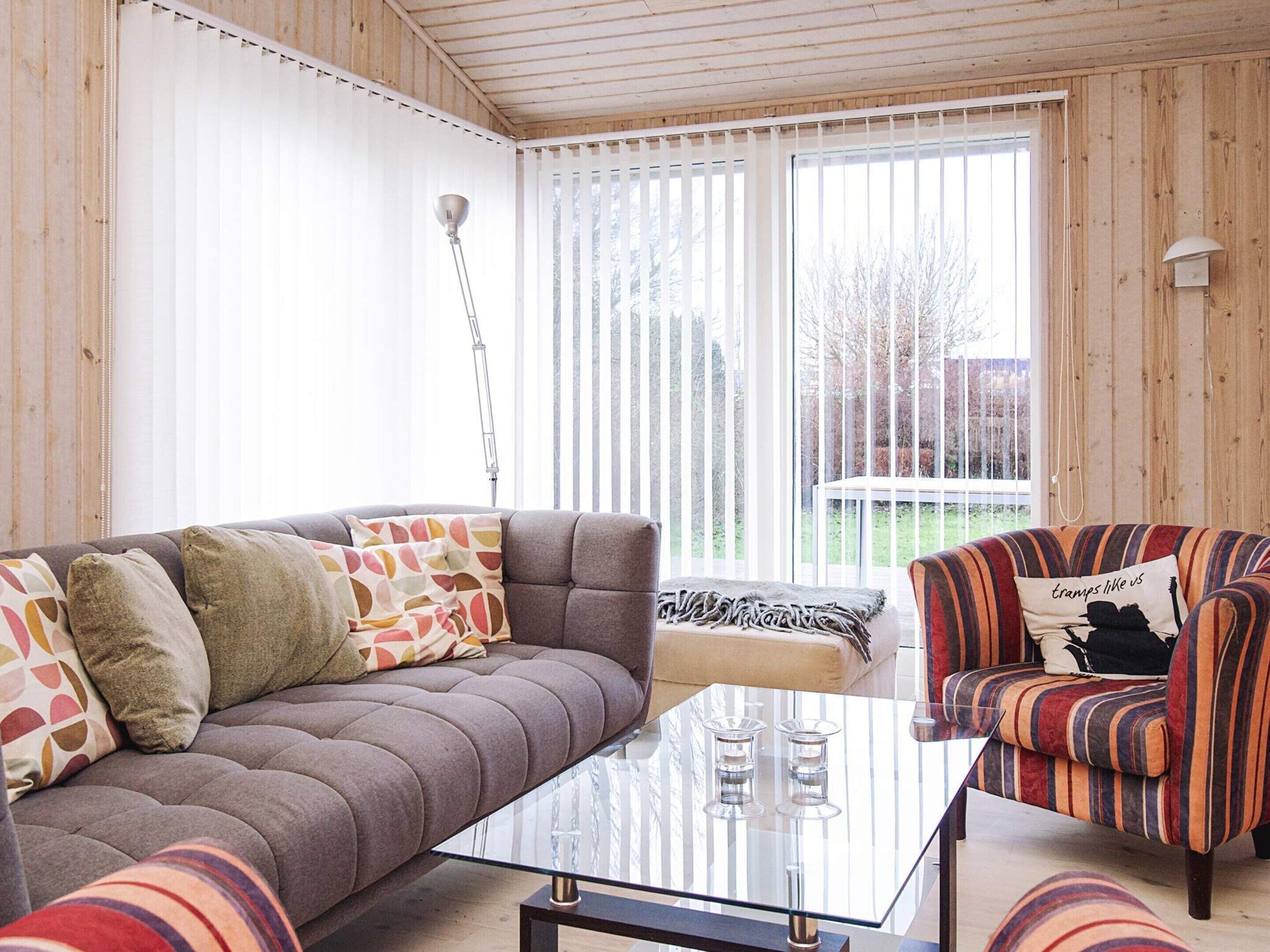 A cozy living room with a grey sofa, striped armchair, and a glass coffee table.