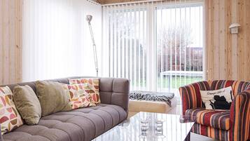 A cozy living room with a grey sofa, striped armchair, and a glass coffee table.
