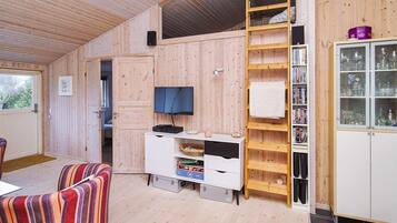 A compact living space with a wooden interior, a television, a bookshelf, and a cabinet with glass doors.