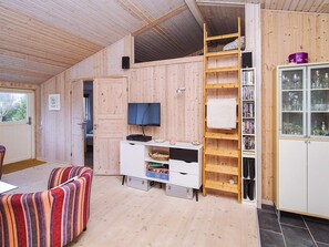 A compact living space with a wooden interior, a television, a bookshelf, and a cabinet with glass doors. - 6 Person Holiday Home in Slagelse (Slagelse)