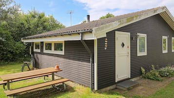A small cabin with a single door, a window, and a picnic table in front.