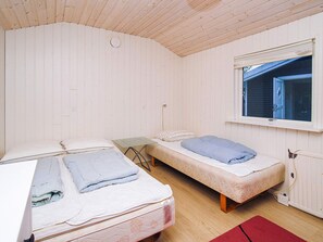 Un alojamiento pequeño de una sola habitación con dos camas, una mesita y una ventana.