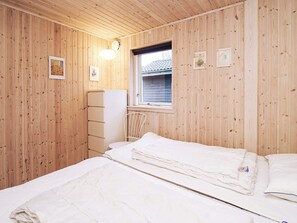 A small, cozy room with wooden walls, a single bed, a white dresser, and a window with a view of a house. - 6 Person Holiday Home in Slagelse (Slagelse)