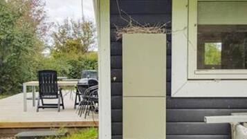 Un edificio pequeño con un porche, una mesa y sillas.