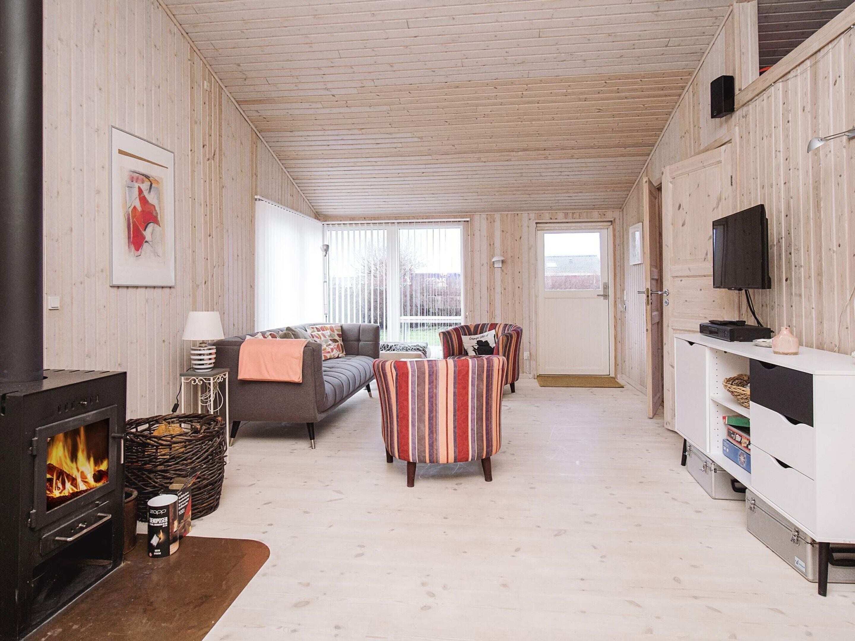 A cozy living room with a fireplace, a sofa, striped armchairs, and a television.