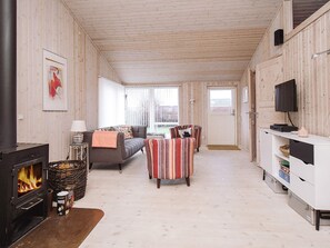 A cozy living room with a fireplace, a sofa, striped armchairs, and a television. - 6 Person Holiday Home in Slagelse (Slagelse)