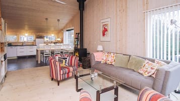 A cozy cabin interior with a dining area, a sofa, and a fireplace.
