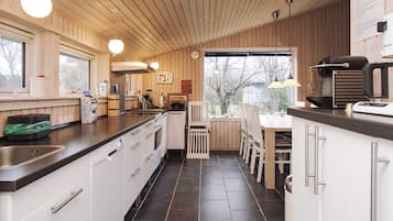 A modern kitchen with wooden paneling, a black countertop, and a view of the outdoors.
